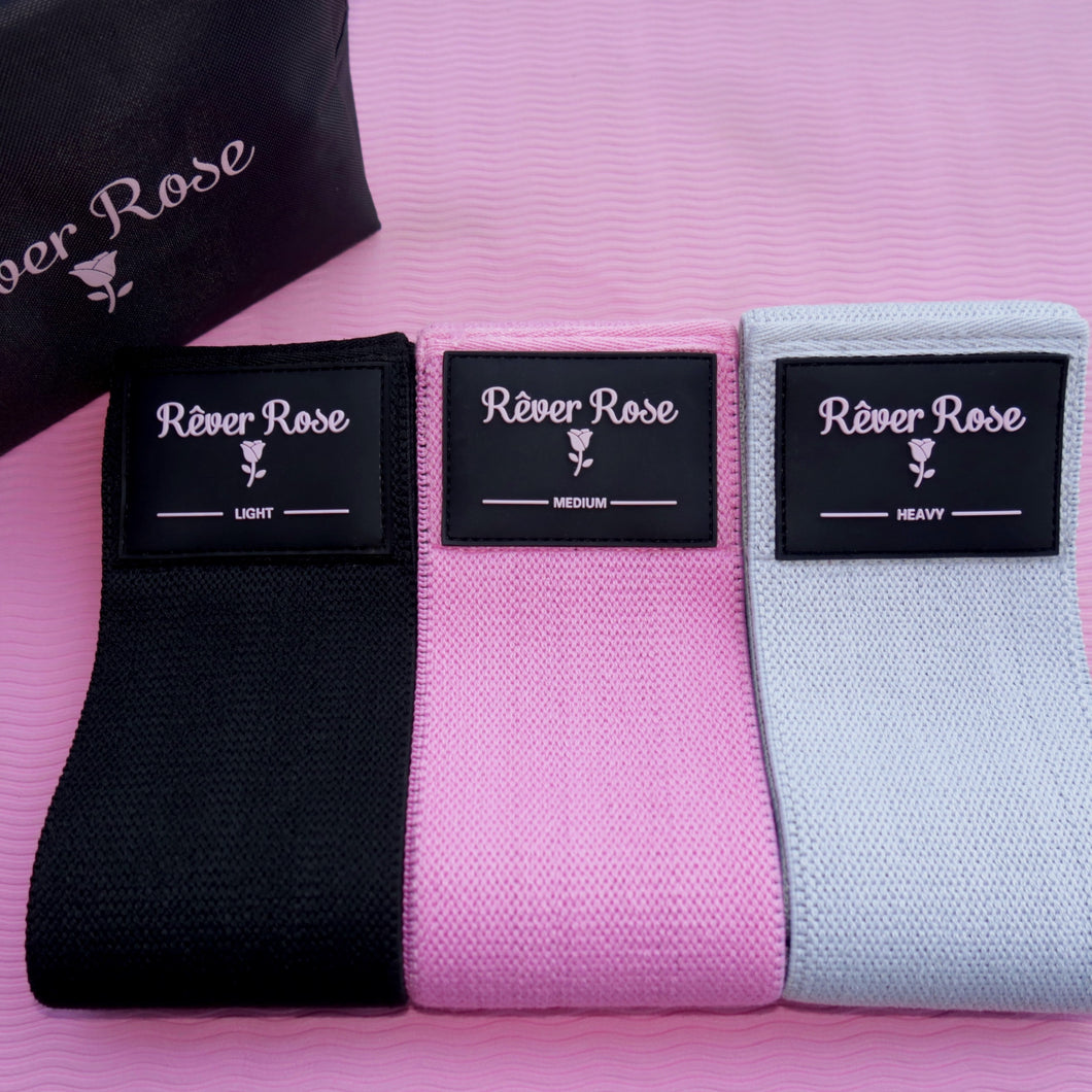 Three resistance bands, black, pink and grey with a pouch.